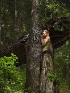 Young girl leaning against tree in forest